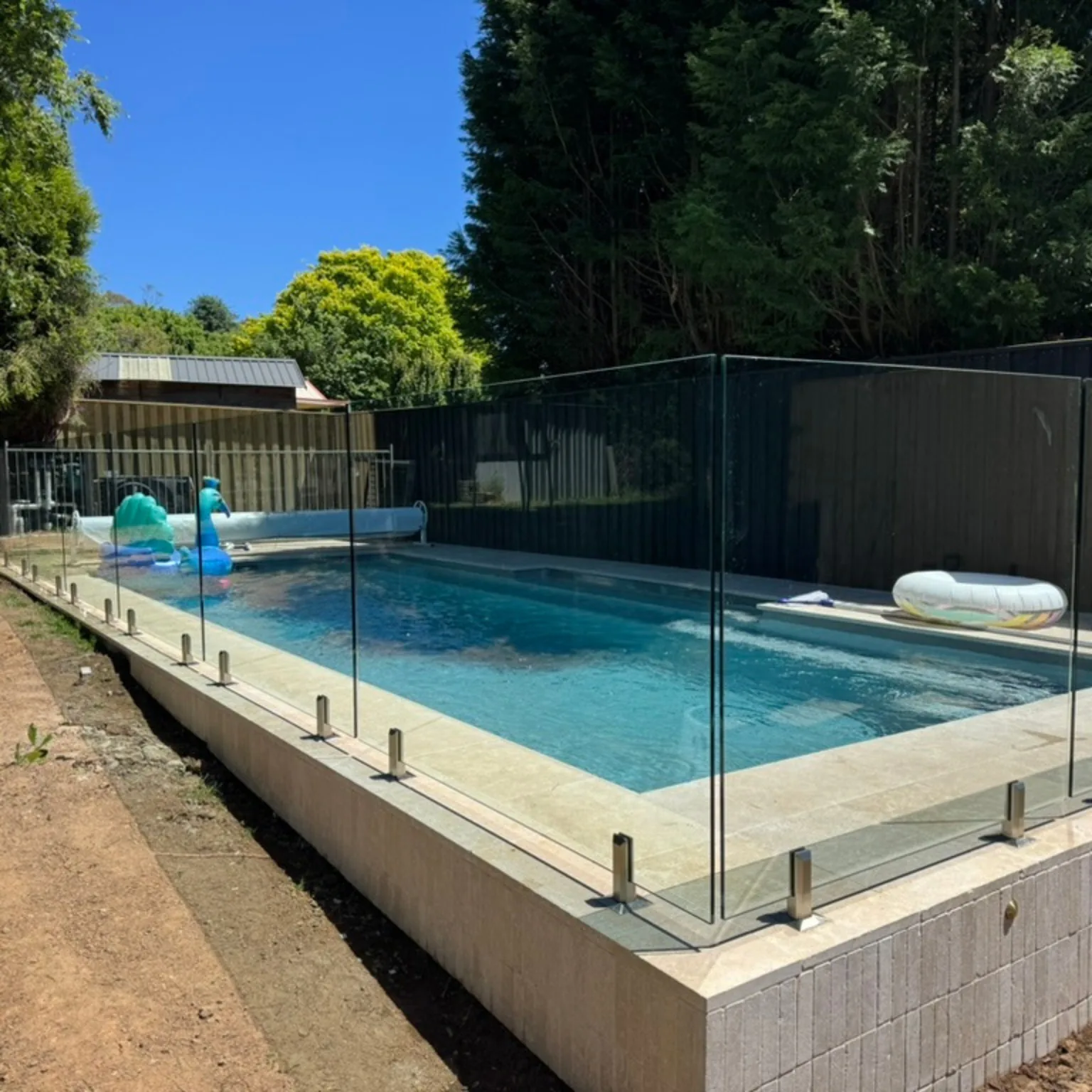 Cierre perimetral de vidrio para piscina residencial con jardín